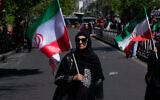 A woman carries an Iranian flag in a mourning ceremony marking the 40th day since the death of Iranian Supreme Leader Ayatollah Ali Khamenei, who was killed in the US and Israel strikes, in Tehran, Iran, April 9, 2026. (AP Photo/Vahid Salemi)