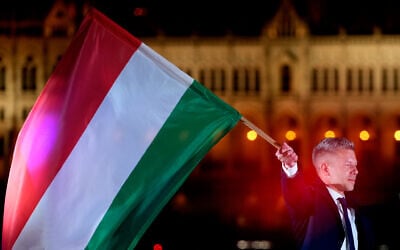 Peter Magyar, the leader of the opposition Tisza party, waves a national flag after a parliamentary election in Budapest, Hungary, on April 12, 2026. (AP Photo/Darko Bandic)