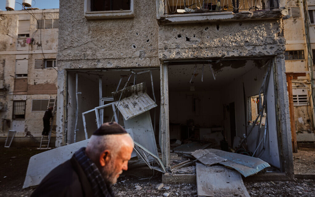 A man walks past a damaged residential building after it was struck by a Hezbollah rocket fired from Lebanon, in Nahariya, northern Israel, April 13, 2026. (AP Photo/Ariel Schalit)