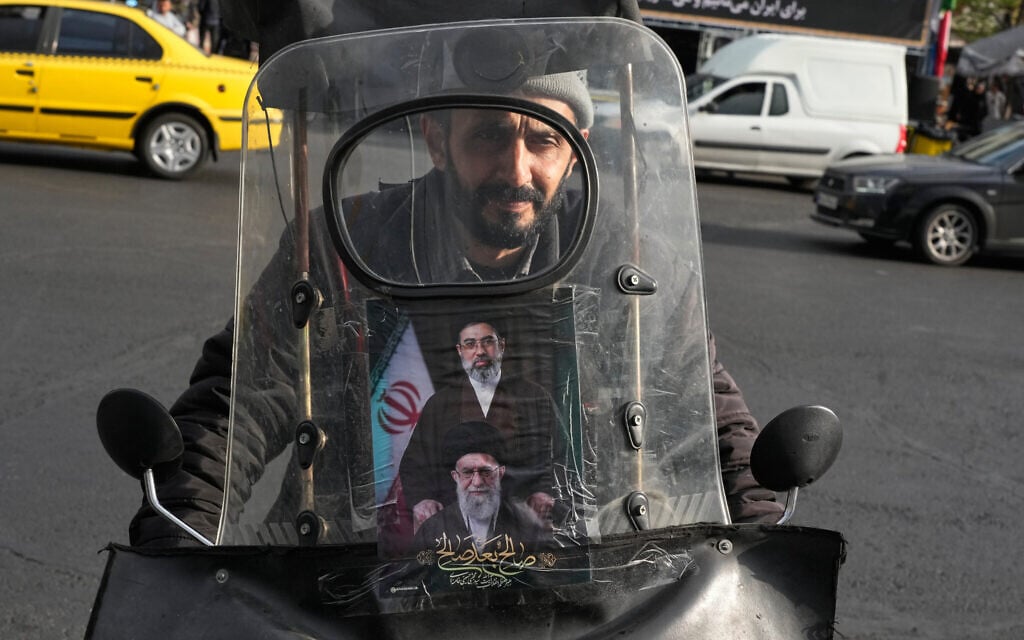 A man drives his motorbike with a poster on its windshield depicting Iran's Supreme Leader Ayatollah Mojtaba Khamenei, top, and his father, the slain supreme leader Ayatollah Ali Khamenei, who was killed in the US and Israel strikes on Feb. 28, in downtown Tehran, Iran, Monday, April 13, 2026. (AP Photo/Vahid Salemi)