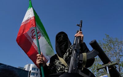 Illustrative: A woman member of the Basij paramilitary, affiliated with Iran's Revolutionary Guard, holds her gun and an Iranian flag during a state-organized rally in support of the supreme leader marking National Girl's Day in Tehran, Iran, April 17, 2026. (AP Photo/Vahid Salemi)
