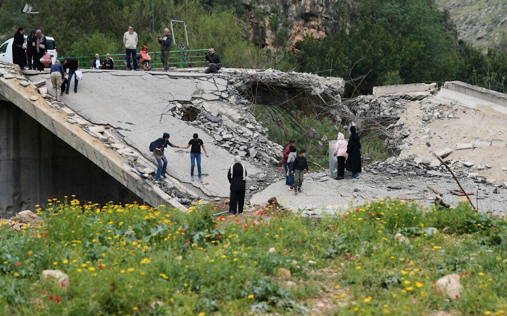 People cross over a destroyed bridge as they return to their villages following a ceasefire between Lebanon and Israel, in Tayr Felsay village near the city of Tyre, southern Lebanon, April 19, 2026. (AP/Bilal Hussein)