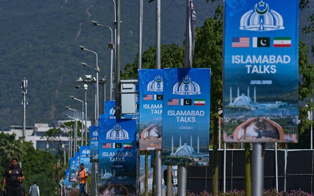 Workers walk past billboards near the Serena Hotel ahead of the second round of negotiations between the US and Iran, in Islamabad, Pakistan, April 20, 2026. (AP Photo/Anjum Naveed)