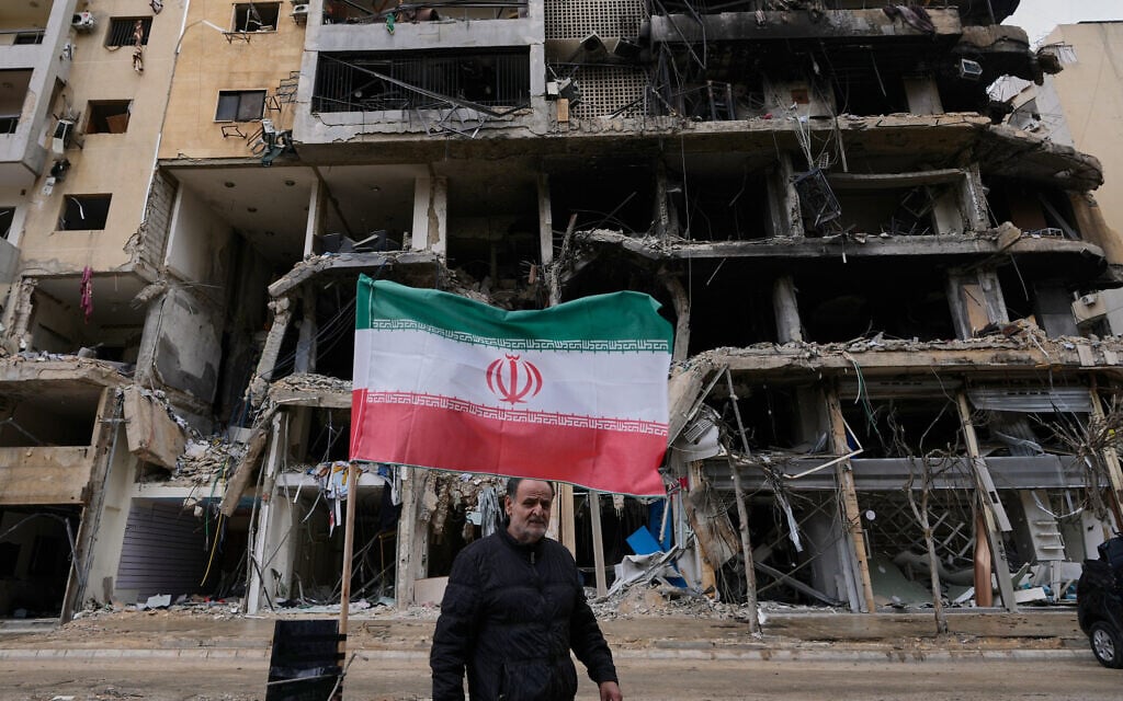 A man passes next to an Iranian flag placed in front of a destroyed building, following a ceasefire between Hezbollah and Israel, in Dahiyeh, Beirut's southern suburbs, Lebanon, April 20, 2026. (AP Photo/Hussein Malla)