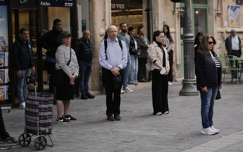People stand still as a two minute siren sounds across Israel, marking Memorial Day, in Jerusalem, April 21, 2026. (AP Photo/Mahmoud illean)