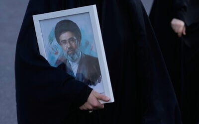 A woman holds a picture of the Iranian supreme leader Ayatollah Mojtaba Khamenei in a memorial for school children who were killed during a strike on a school in southern town of Minab, in downtown Tehran, Iran, April 7, 2026. (AP/Vahid Salemi, File)