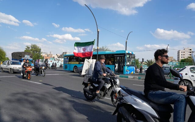 A man rides his motorbike that is adorned with an Iranian national flag, in southern Tehran, Iran, Tuesday, April 21, 2026. (AP Photo/Vahid Salemi)