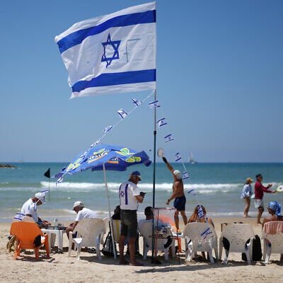 People stand on the beach during Independence Day celebrations in Tel Aviv, April 22, 2026. (AP/Ariel Schalit)