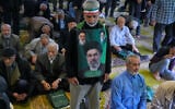 An Iranian worshipper wears a banner showing portraits of the Supreme Leader Ayatollah Mojtaba Khamenei, bottom, late supreme leader Ayatollah Ali Khamenei, top right, and the late revolutionary founder Ayatollah Khomeini, during Friday prayers ceremony at the Tehran University campus, in Tehran, Iran, on April 24, 2026. (AP Photo/Vahid Salemi)