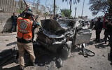 Palestinian crews work on a destroyed car after it was struck in an Israeli strike in Gaza City, April 28, 2026. (AP Photo/Jehad Alshrafi)