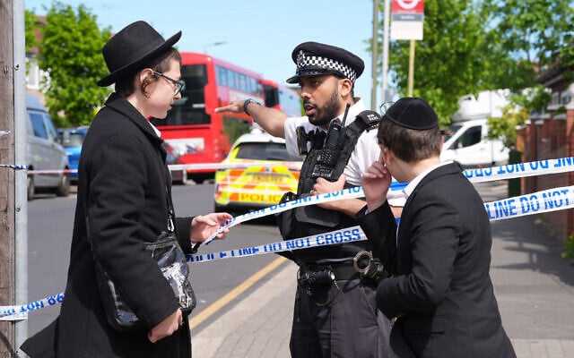 A police officer talks with two boys where two people were stabbed, in Golders Green neighborhood, that has a large Jewish community, in London, April 29, 2026. (Lucy North/PA via AP)