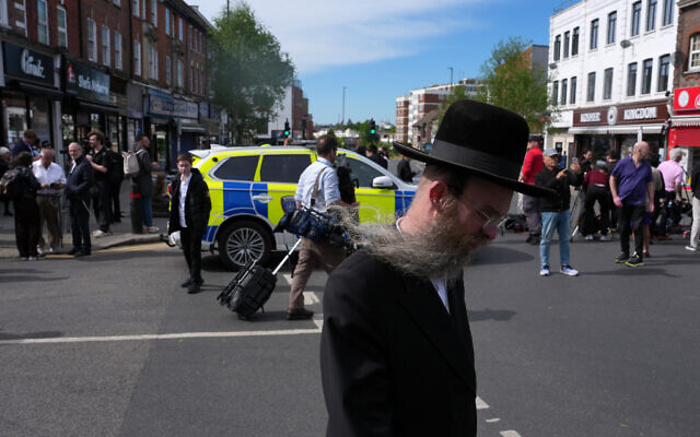 A man walks past a road blocked by police after two Jewish men were stabbed in Golders Green neighborhood of London, April 29, 2026. (AP/Kin Cheung)