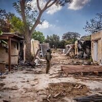 Israeli soldiers look around the destruction caused by Hamas terrorists in Kibbutz Kfar Aza, near the Israeli-Gaza border, in southern Israel, October 15, 2023. (Oren Ben Hakoon/Flash90)