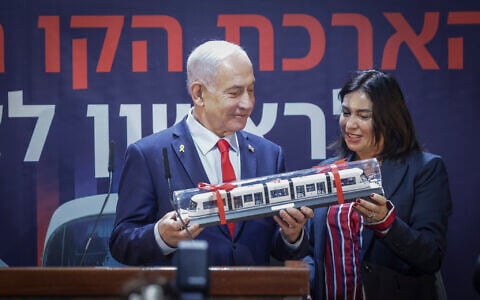Transportation Minister Miri Regev, right, and Prime Minister Benjamin Netanyahu hold a toy train at a ceremony marking the start of works on a new light rail in Rishon Lezion, central Israel, December 25, 2025. (Tal Gal/Flash90)