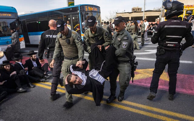 Ultra-Orthodox men block a road and clash with police during a protest against the jailing of a yeshiva students who failed to comply with an army recruitment order, at the entrance to Jerusalem, February 16, 2026. (Chaim Goldberg/Flash90)