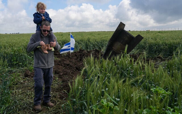 A man and his child next to a fragment of a missile fired from Iran toward Israel, intercepted by Israeli air defense systems, seen lodged in the ground in the Golan Heights, April 8, 2026. (Ayal Margolin/Flash90) A man and his child next to a fragment of a missile fired from Iran toward Israel, intercepted by Israeli air defense systems, seen lodged in the ground in the Golan Heights, April 8, 2026. (Ayal Margolin/Flash90)