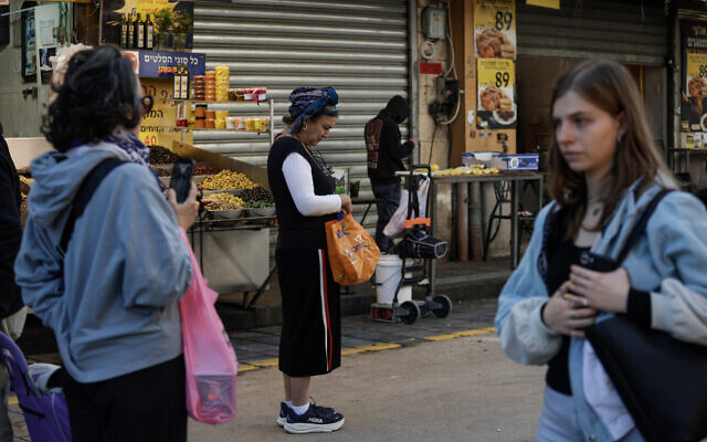 People stand still at the Mahane Yehuda market in Jerusalem, as a two-minute siren is sounded across Israel to mark Holocaust Remembrance Day on April 14, 2026. (Rachel Alroey/Flash90)