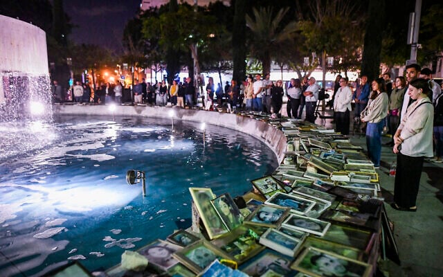People stand in a moment of silence beside photos of victims of terror attacks and fallen Israeli soldiers at Dizengoff Square in Tel Aviv at the start of Israel’s Memorial Day, April 20, 2026. (Avshalom Sassoni/ Flash90)