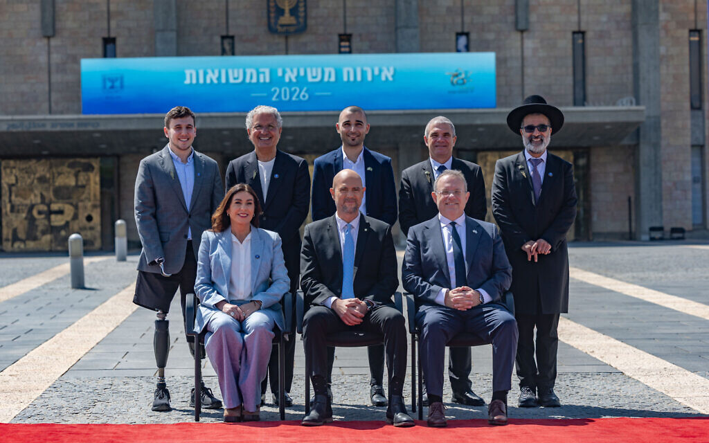 Knesset Speaker Amir Ohana and Transportation Minister Miri Regev pose for a group picture with the torch lighters of the Independence Day state ceremony, at the Knesset, in Jerusalem, on April 20, 2026. (Yonatan Sindel/Flash90)
