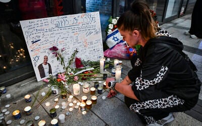 People gather outside a Pizza Hut branch in Petah Tikva, lighting candles and placing flowers in memory of employee Yemanu Binyamin Zelka, who was stabbed to death there, April 25, 2026. (Avshalom Sassoni/Flash90)