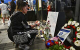 People gather outside a Pizza Hut branch in Petah Tikva, lighting candles and placing flowers in memory of employee Yemanu Binyamin Zelka, who was killed at the site days earlier, April 25, 2026. (Avshalom Sassoni/Flash90)