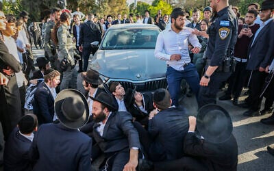 Ultra-Orthodox men block a road during a protest against the jailing of yeshiva students who dodge the military draft, near Bnei Brak, April 28, 2026. (Flash90)