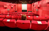 A woman sits alone in a Frankfurt, Germany, cinema in November 2021. (Frank Rumpenhorst/picture alliance via Getty Images via JTA)