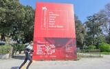 A man running in front of a sign for the Venice Biennale in Italy in an undated photo. (Stefano Mazzola via Getty Images via JTA)