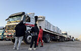 Trucks transporting humanitarian aid wait to enter through the Egyptian side of the Rafah border crossing with the Gaza Strip on March 19, 2026.(Amr Adel/AFP)