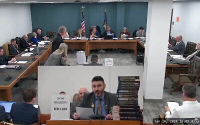New Hampshire GOP state Rep. Matt Sabourin dit Choinière (center) testifies before a state committee on his proposed amendment to add a Holocaust denier to the state's Holocaust education commission, January 14, 2026. He is flanked by a stack of Holocaust-denial books. (Screenshot via JTA)