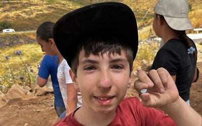 Six grader Alon Horowitz finds a rare 'Nicolo' stone, likely dating back at least 1,500 years, during a community excavation at Korazim National Park, in a discovery announced on June 1, 2026. (Korazim excavation team/Israel Nature and Parks Authority)