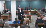 New Hampshire GOP state Rep. Travis Corcoran (center) walks out of his own disciplinary hearing for tweeting a "final solution" reference at a Jewish colleague, April 27, 2026. (Screenshot via JTA)