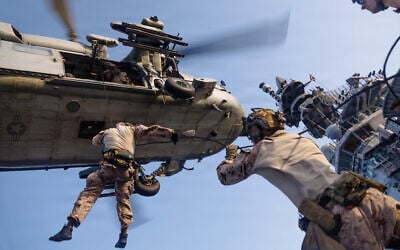 This photo released on May 12, 2026 shows US Marines with Maritime Raid Force rappelling out of an MH-60S Sea Hawk, assigned to Helicopter Sea Combat Squadron 25, during helicopter and roping sustainment training aboard the forward-deployed amphibious assault ship USS Tripoli at sea on May 8, 2026. (US Marine Corps photo)