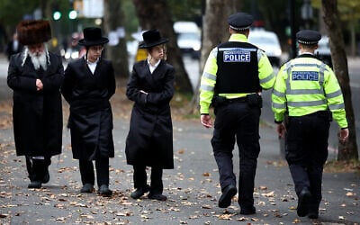 Members of the local Jewish community look on as Metropolitan Police officers patrol the streets in Stamford Hill, north London on October 2, 2025. (Henry Nicholls/AFP)