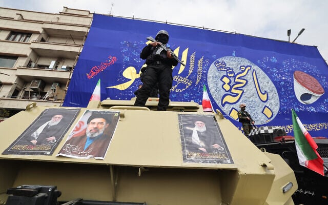 A member of Iran's security forces stands guard on an armored vehicle plastered with the pictures of, from left, Iran's slain supreme leader Ali Khamenei, his son and successor Mojtaba Khamenei and founding Supreme Leader Ruhollah Khomeini, during the funeral procession of Revolutionary Guard commanders killed in the regional war, on March 11, 2026. (Atta KENARE / AFP) A member of Iran's security forces stands guard on an armored vehicle plastered with the pictures of, from left, Iran's slain supreme leader Ali Khamenei, his son and successor Mojtaba Khamenei and founding Supreme Leader Ruhollah Khomeini, during the funeral procession of Revolutionary Guard commanders killed in the regional war, on March 11, 2026. (Atta KENARE / AFP)