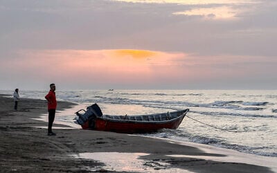 A man stands near a boat moored along a beach on the Caspian Sea coast in Sorkhrud in Iran's northern Mazandaran province on March 24, 2026. (ATTA KENARE / AFP)
