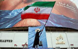 A woman waves an Iranian flag in front of an anti-US billboard referring to US President Donald Trump and the Strait of Hormuz at Valiasr Square in Tehran, Iran, on May 5, 2026. (AFP)