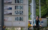 People ride bicycles past a digital board displaying fuel prices near a gas station in Sofia, Bulgaria, on May 6, 2026. (Nikolay DOYCHINOV/AFP)