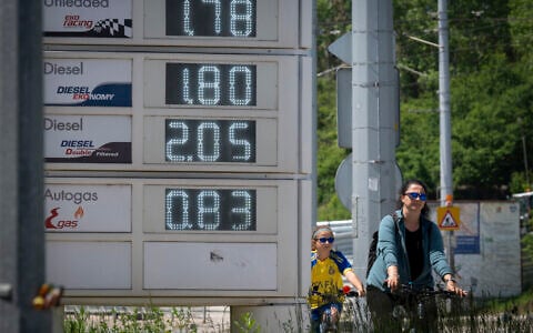 People ride bicycles past a digital board displaying fuel prices near a gas station in Sofia, Bulgaria, on May 6, 2026. (Nikolay DOYCHINOV/AFP)