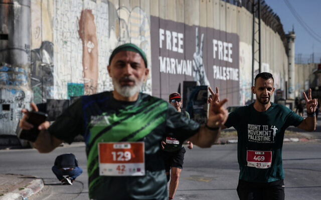 Palestinians and foreign nationals runs past Israel's West Bank security barrier, as they take part in the annual Palestine Marathon, in the West Bank city of Bethlehem on May 8, 2026. (HAZEM BADER / AFP)