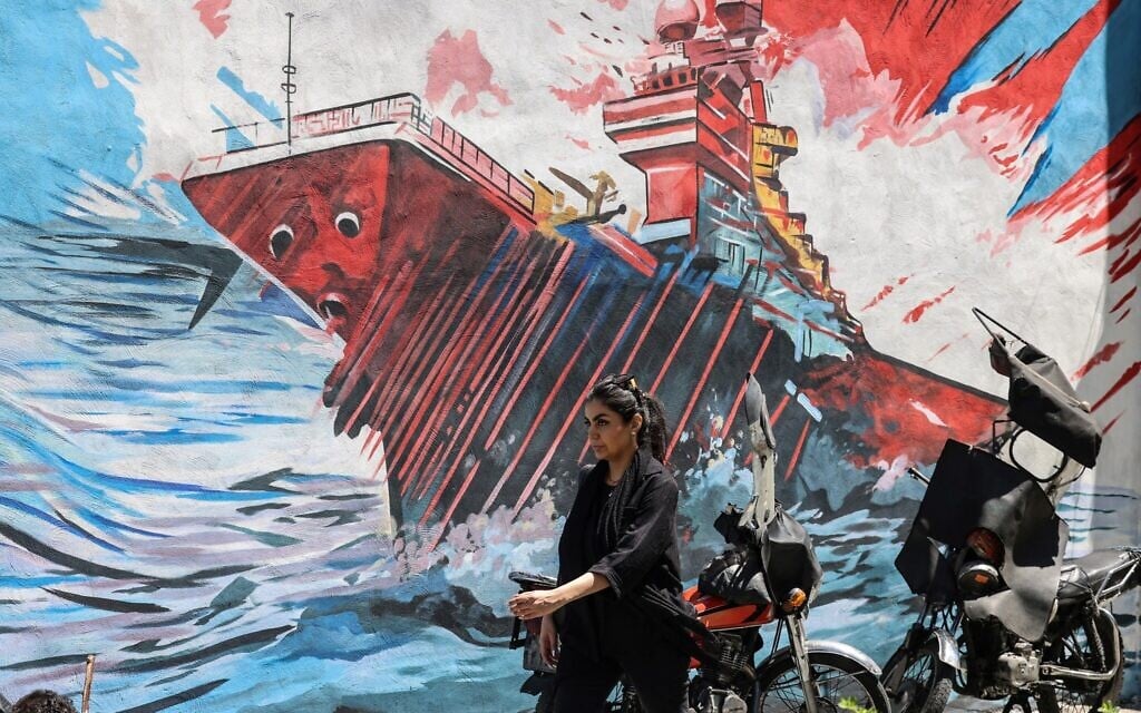 An Iranian woman walks past an anti-US and anti-Israel mural painted on a wall, in the Iranian capital, Tehran, on May 10, 2026. (Atta Kenare/AFP)