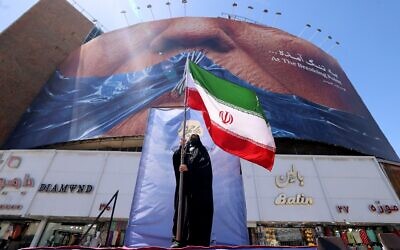 A woman holds the Iranian flag as she stands in front of an anti-US billboard in Tehran, Iran, on May 10, 2026. (ATTA KENARE / AFP) A woman holds the Iranian flag as she stands in front of an anti-US billboard in Tehran, Iran, on May 10, 2026. (ATTA KENARE / AFP)
