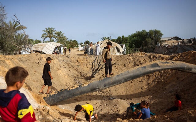 Palestinian children gather around a crater following overnight Israeli bombardment in Khan Younis, in the southern Gaza Strip, on May 19, 2026. (Bashar Taleb / AFP)