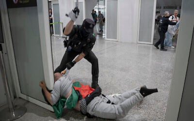 A Basque police officer beats a member of the Global Sumud Flotilla upon their arrival at Bilbao Airport on May 23, 2026. (Idurre Etxaburu / AFP)
