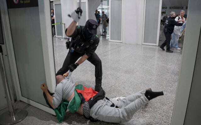 A Basque police officer beats a member of the Global Sumud Flotilla upon their arrival at Bilbao Airport on May 23, 2026. (Idurre Etxaburu / AFP)