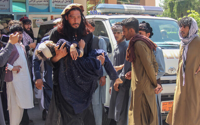 A man carries an injured girl to a hospital for treatment after a truck carrying Afghan families overturned in Jalalabad, Afghanistan, on May 30, 2026. (Aimal Zahir / AFP)