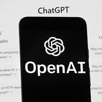 The OpenAI logo is seen on a mobile phone in front of a computer screen which displays the ChatGPT home Screen, March 17, 2023, in Boston, Massachusetts. (AP Photo/Michael Dwyer)