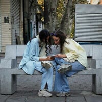 Two women use a smartphone in northern Tehran, Iran, September 28, 2025. (AP Photo/Vahid Salemi, File)