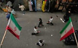 People walk as Iranian flags hang in the Grand Bazaar in Tehran, Iran, May 3, 2026. (AP/Vahid Salemi)