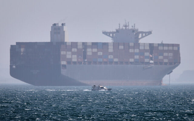 Illustrative: A container ship sits at anchor as a small motorboat passes in the foreground in the Strait of Hormuz off Bandar Abbas, Iran, May 2, 2026. (Amirhosein Khorgooi/ISNA via AP)